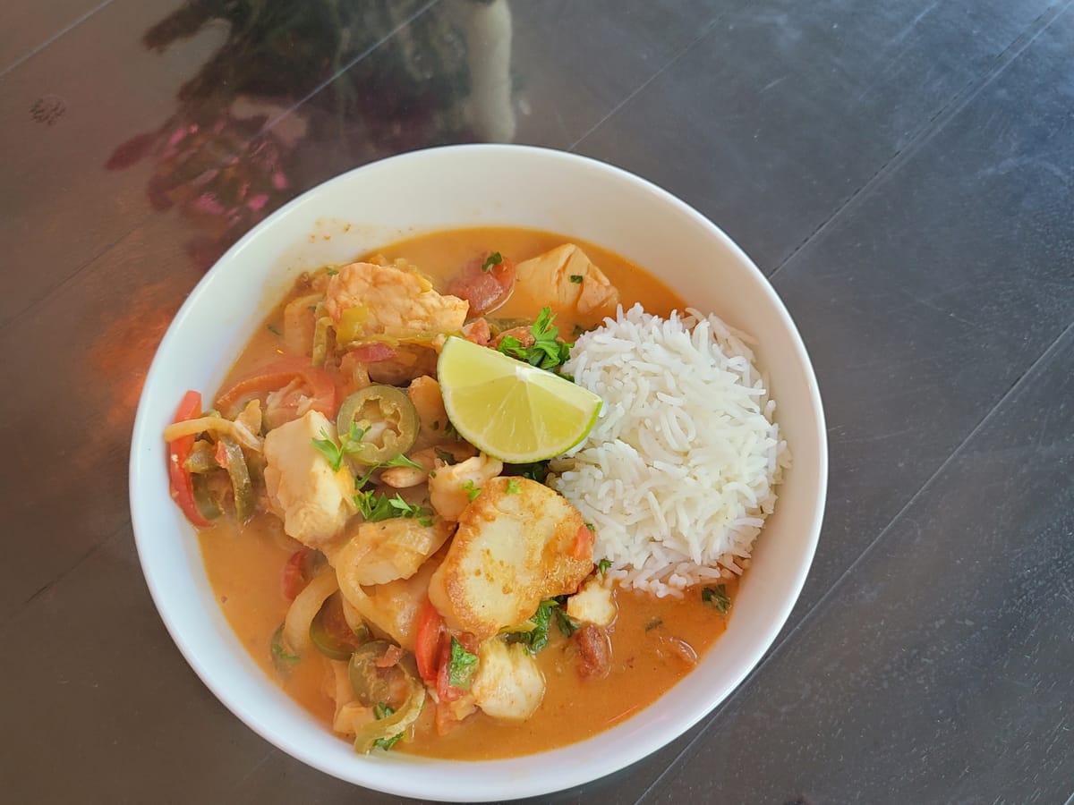 Brazilian fish stew with white fish and shrimp in creamy coconut sauce, served with white rice and fresh lime wedges