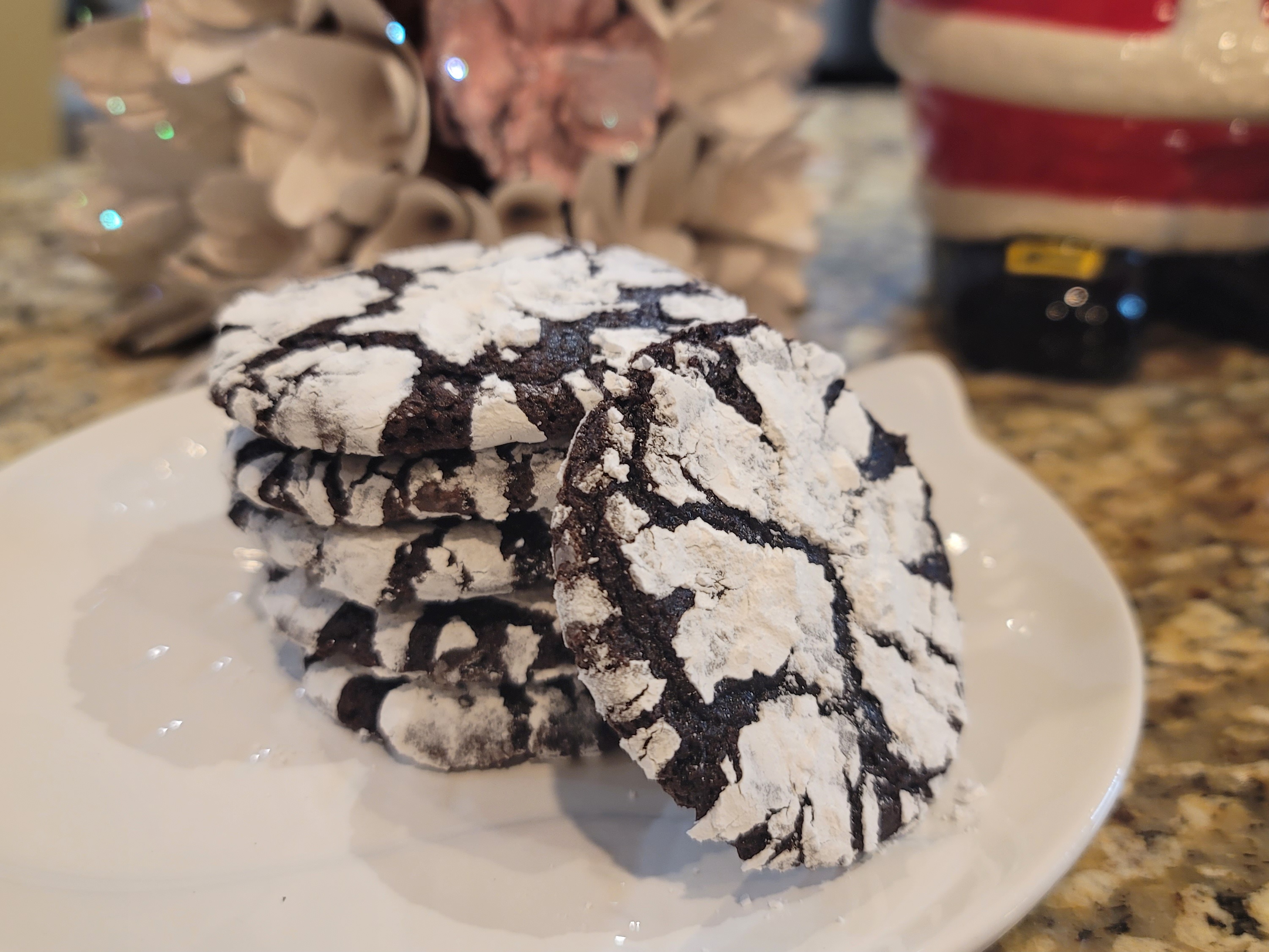 Chocolate crinkle cookies with white powdered sugar coating and dark chocolate cracks, also known as zebra cookies, arranged on a light surface