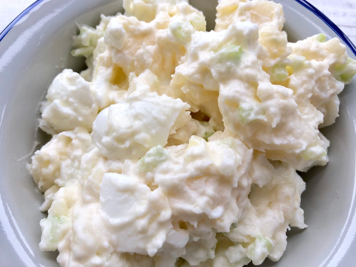 Classic potato salad with diced potatoes, hard-boiled eggs, celery, and fresh green onions in a creamy mayo dressing