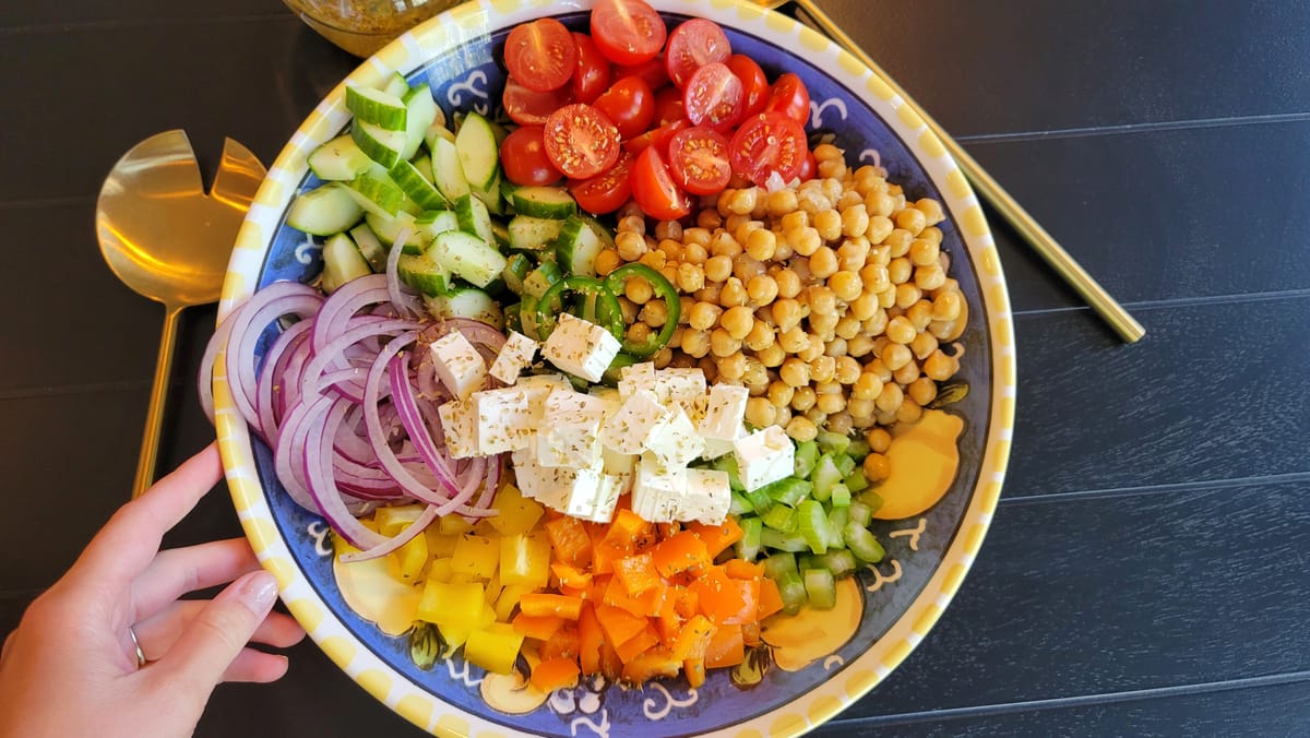 Mediterranean chickpea salad with colorful bell peppers, cherry tomatoes, cucumber, and crumbled feta cheese in a white bowl