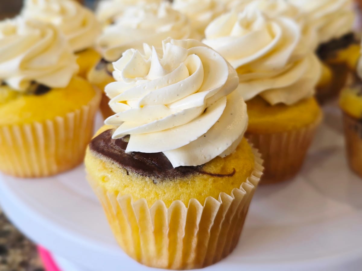 Silky white chocolate Swiss meringue buttercream in a glass bowl with a spatula, showcasing its smooth, creamy texture and glossy finish