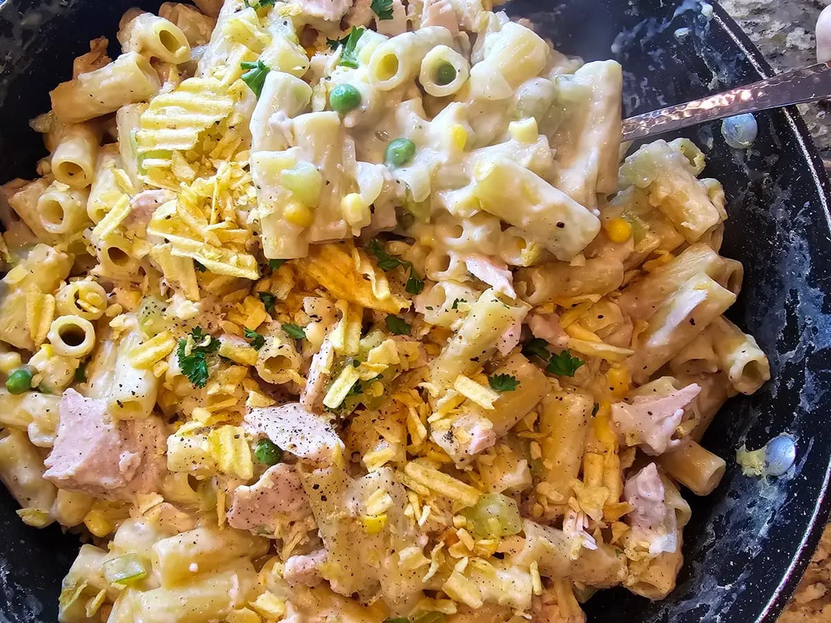Creamy stovetop tuna casserole in a pot topped with crispy golden potato chips and fresh herbs