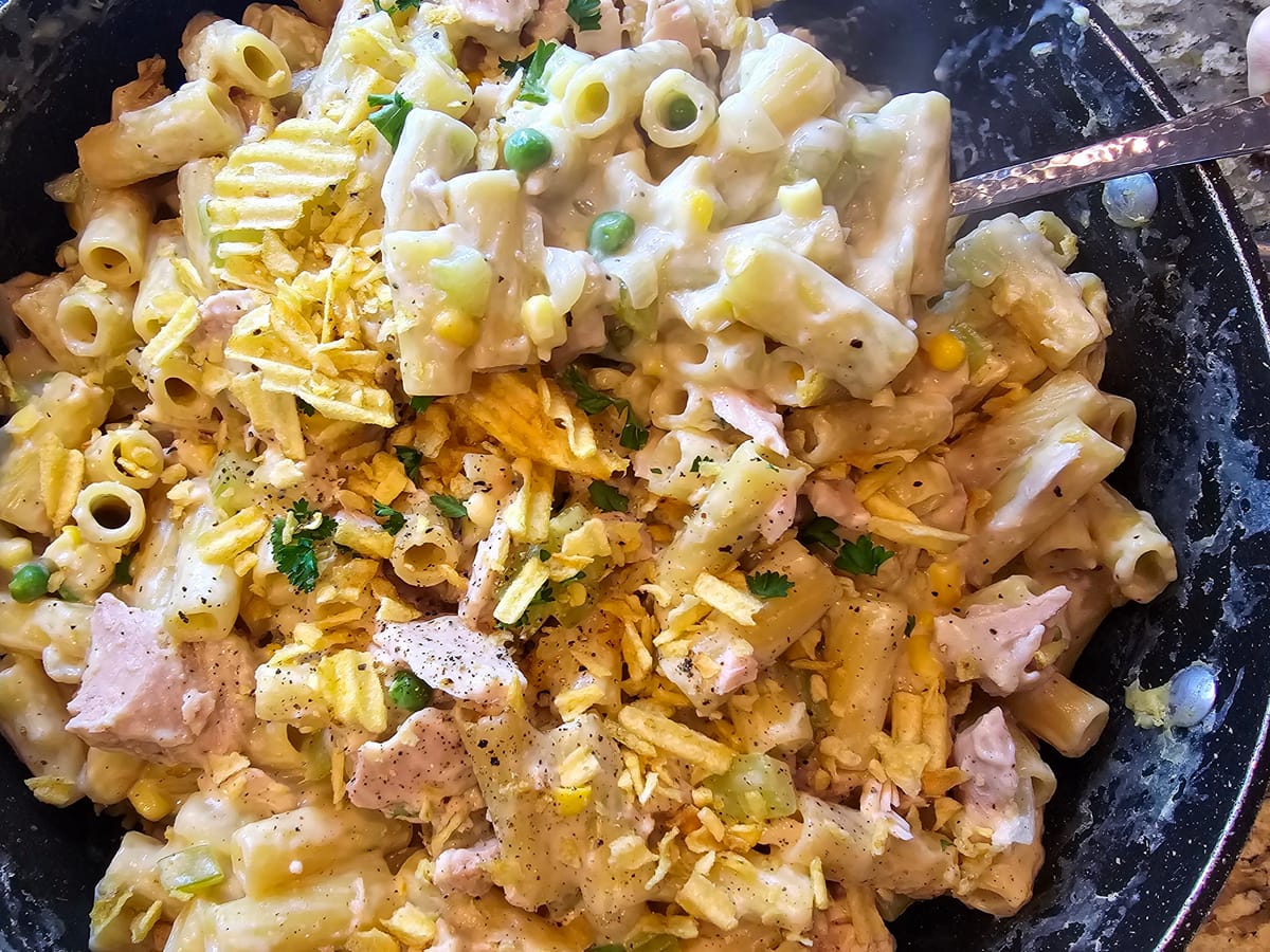 Creamy stovetop tuna casserole in a pot topped with crispy golden potato chips and fresh herbs
