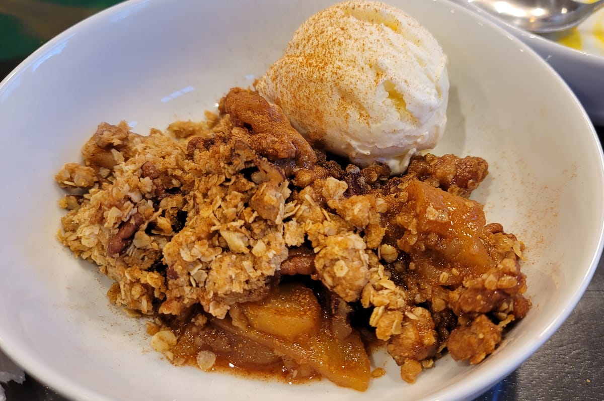 Golden-brown apple crisp with buttery oat crumble topping in a baking dish, showing tender cinnamon-spiced apples underneath