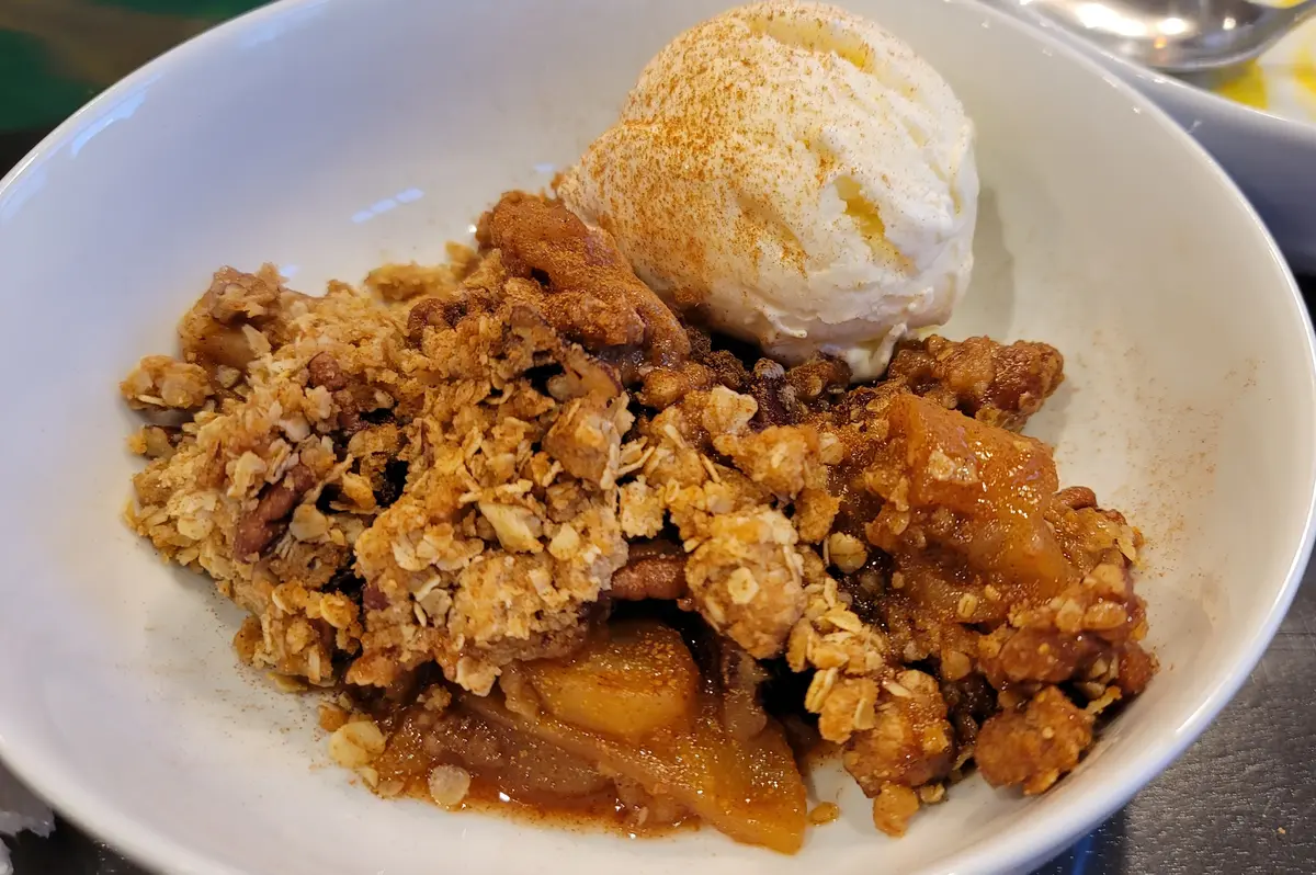 Golden-brown apple crisp with buttery oat crumble topping in a baking dish, showing tender cinnamon-spiced apples underneath