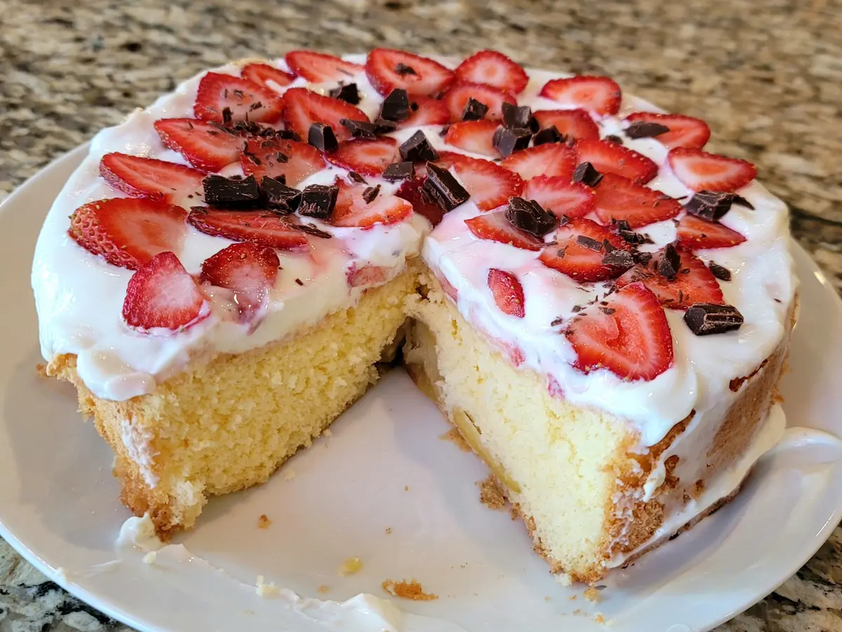 Golden Russian biskvit sponge cake layered with fresh strawberries and topped with chocolate shavings and sour cream frosting