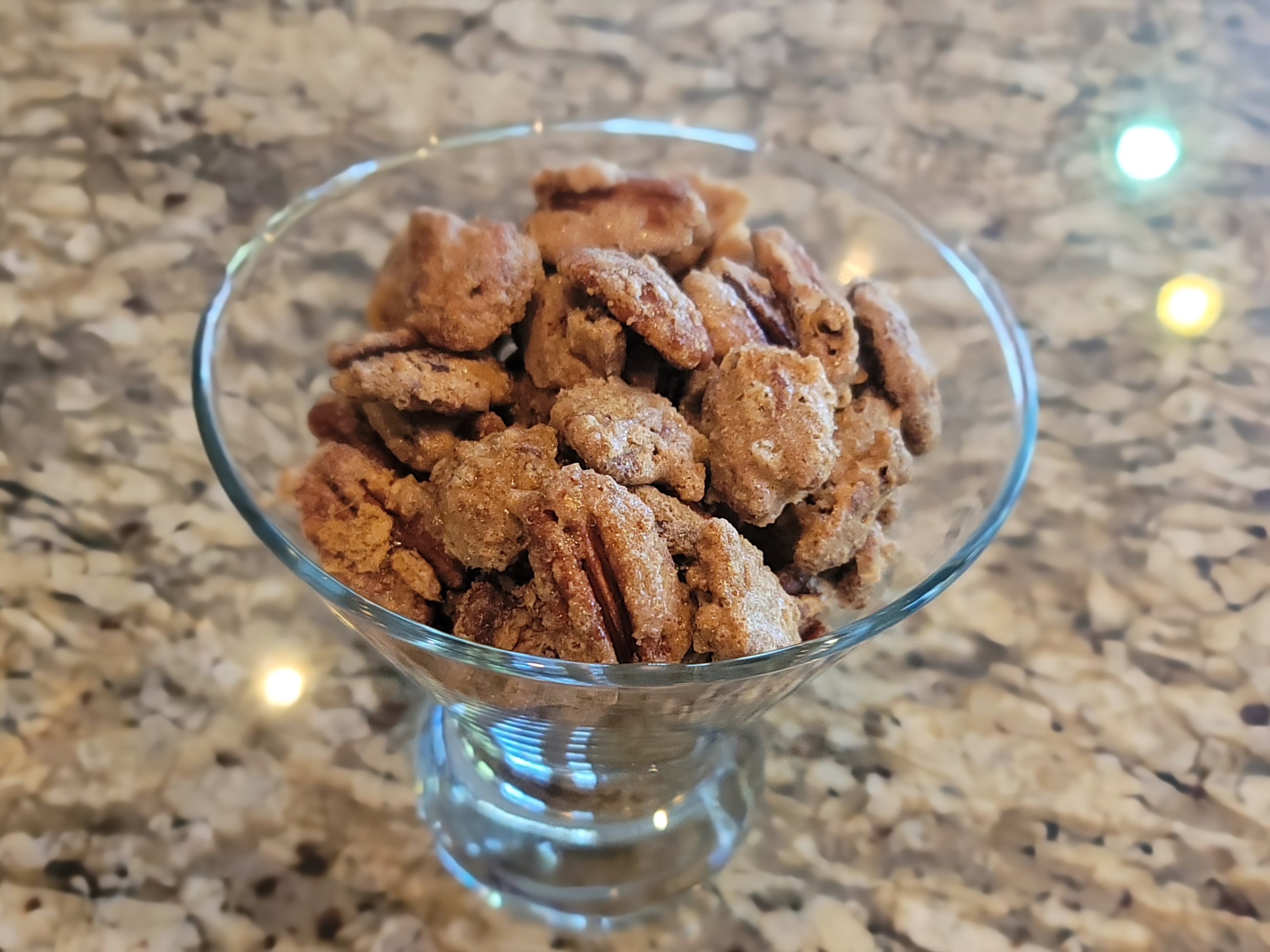 Candied pecans with cinnamon coating spread on parchment paper, golden brown and glistening
