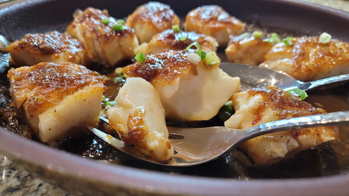 Pan-seared cod fillets with glossy chili-lime glaze, garnished with fresh ginger and chili flakes on a white plate