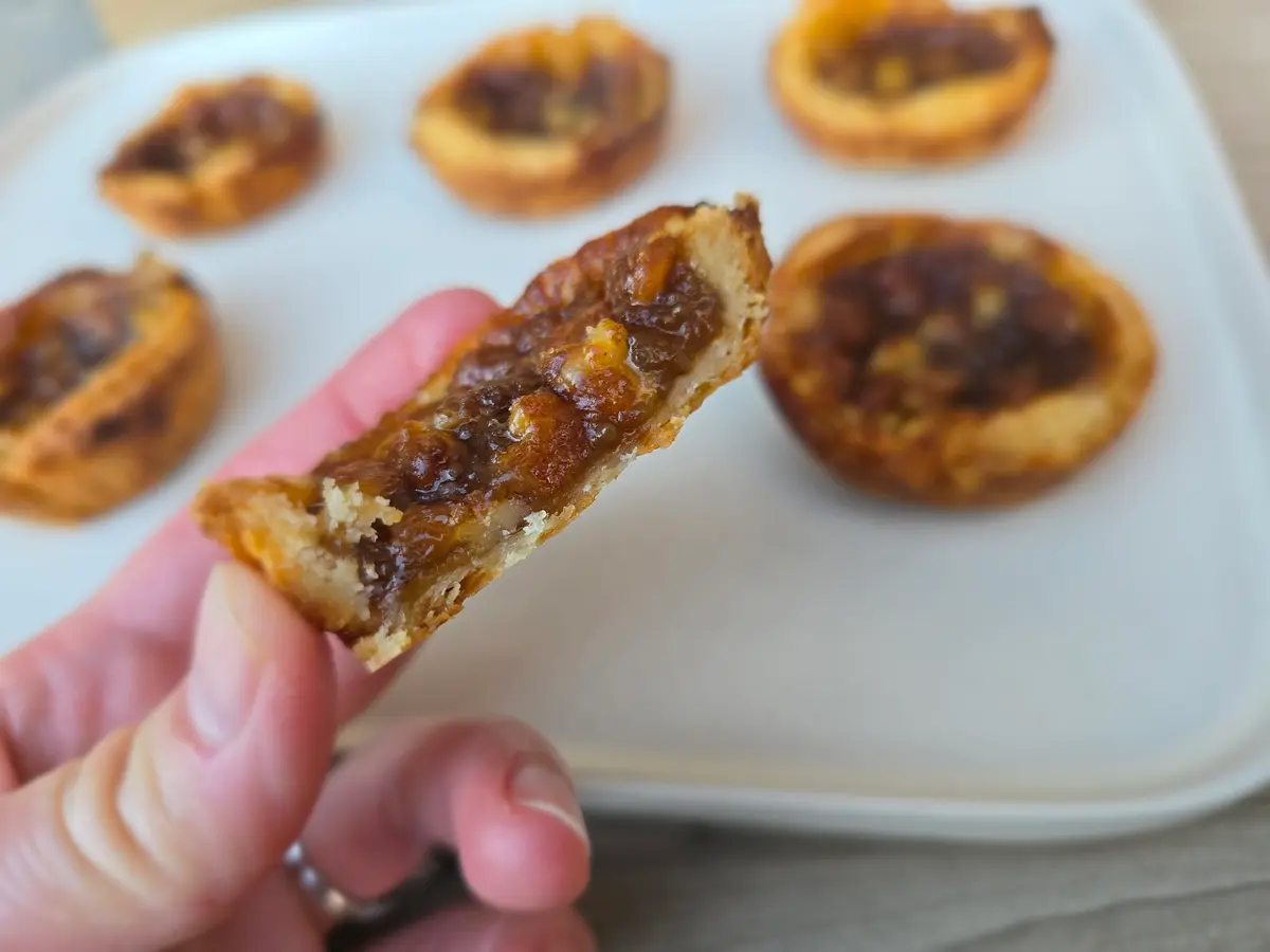 Classic Canadian butter tarts with golden flaky pastry shells and gooey caramelized filling on a white surface