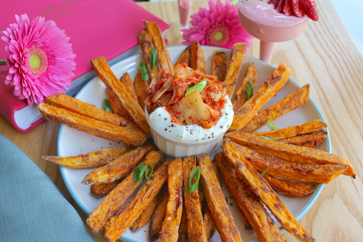 Golden crispy sweet potato fries on parchment paper with paprika seasoning and herbs