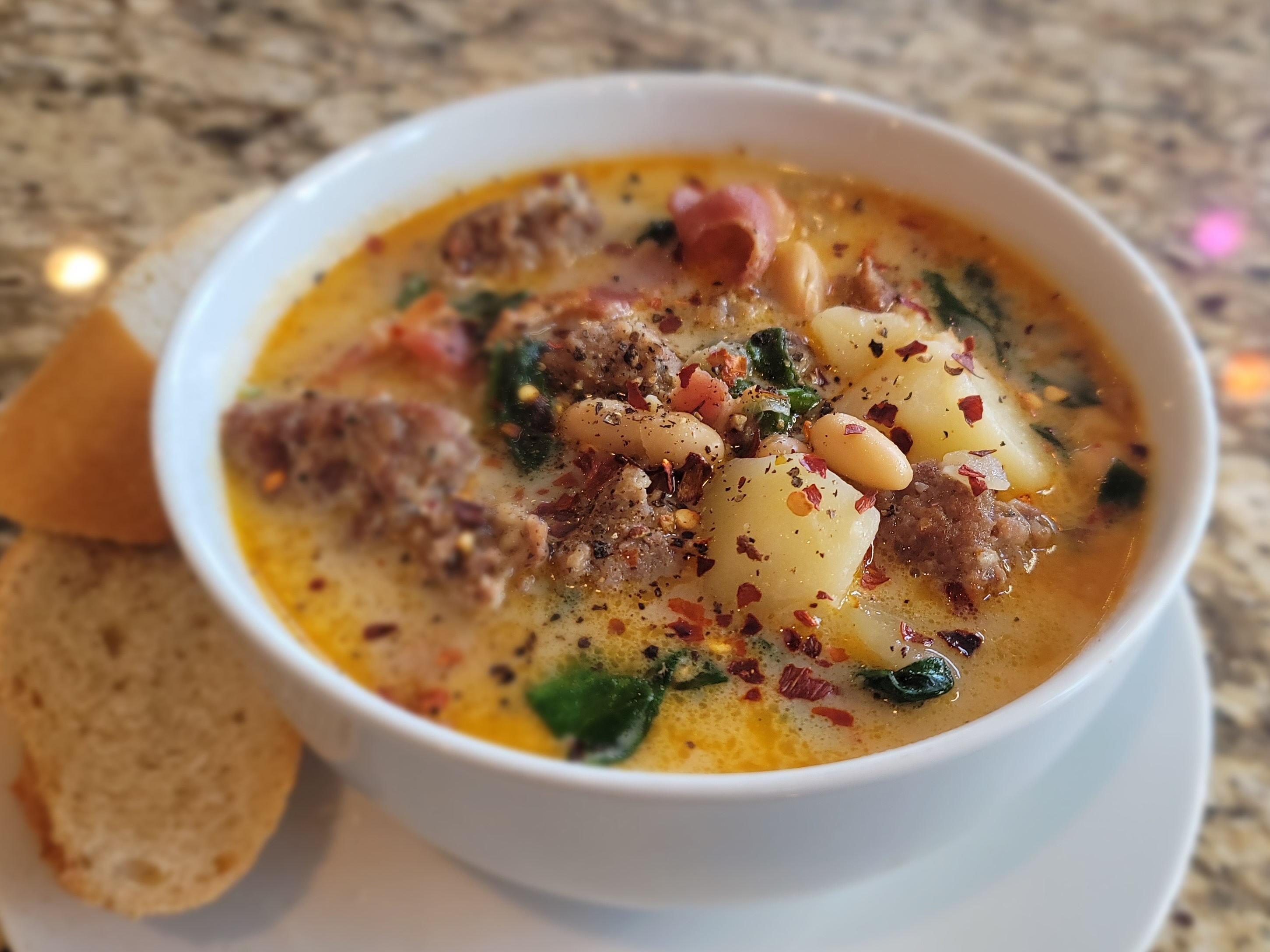 Bowl of creamy Zuppa Toscana soup with Italian sausage, bacon, potatoes, and fresh spinach