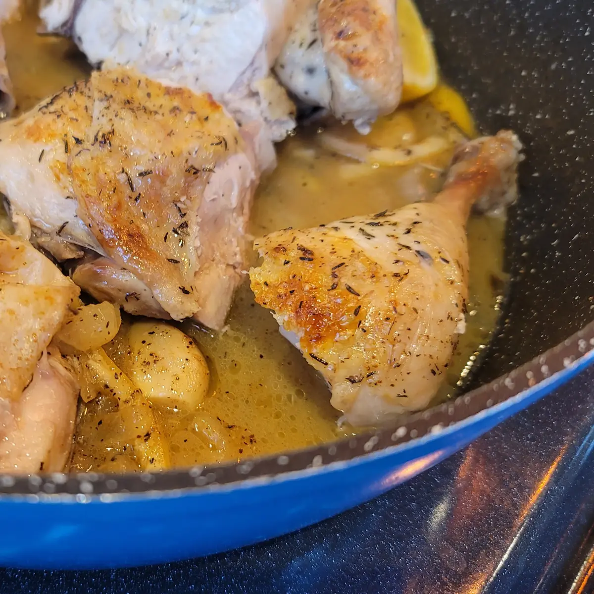 Golden roasted lemon chicken with crispy skin on a white plate, garnished with fresh lemon slices and herbs