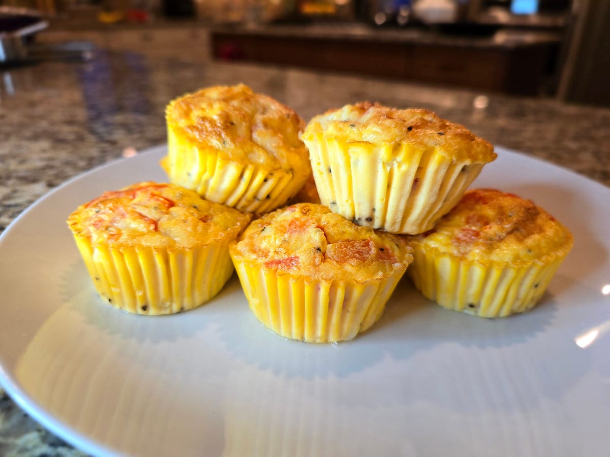 Fluffy cottage cheese egg bites in a muffin tin, golden brown with melted mozzarella and red bell peppers visible