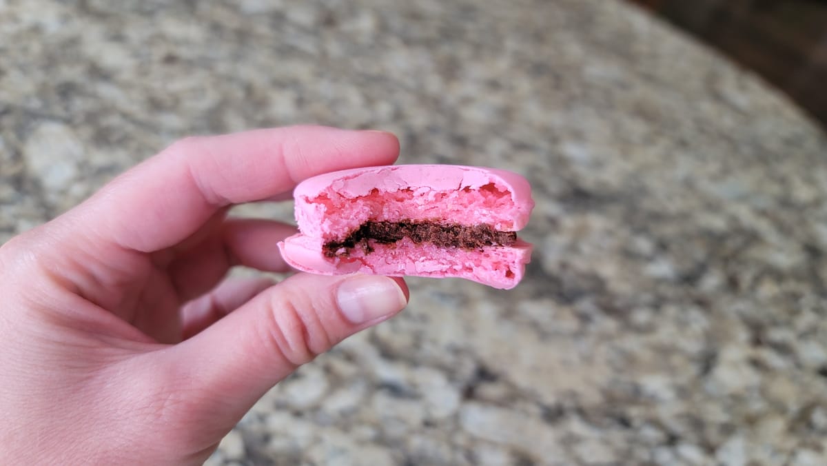Colorful French macarons with chocolate ganache filling stacked on a white surface, showcasing crispy shells and chewy centers
