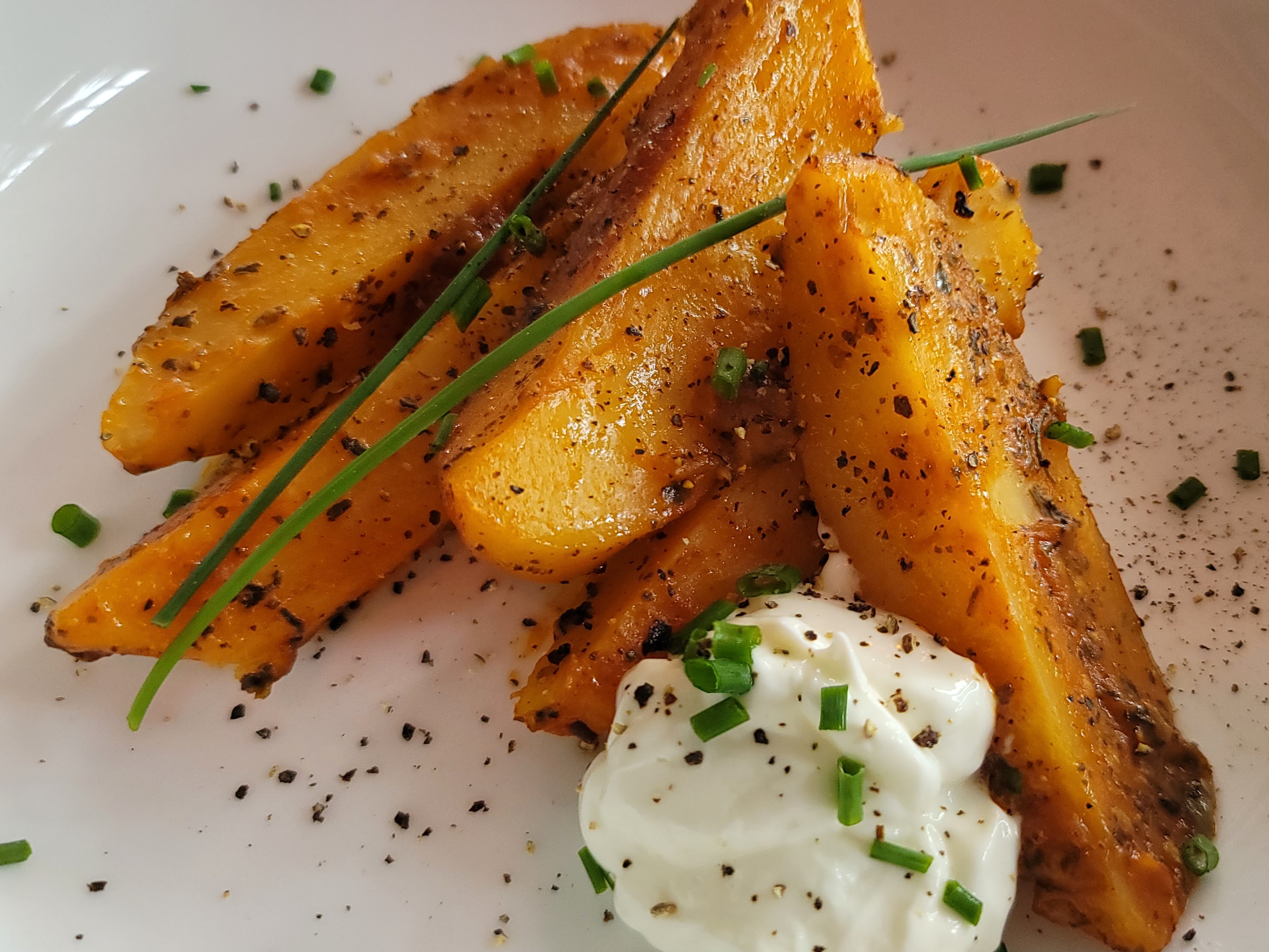 Golden roasted Greek lemon potatoes with crispy edges and fresh herbs on a white plate