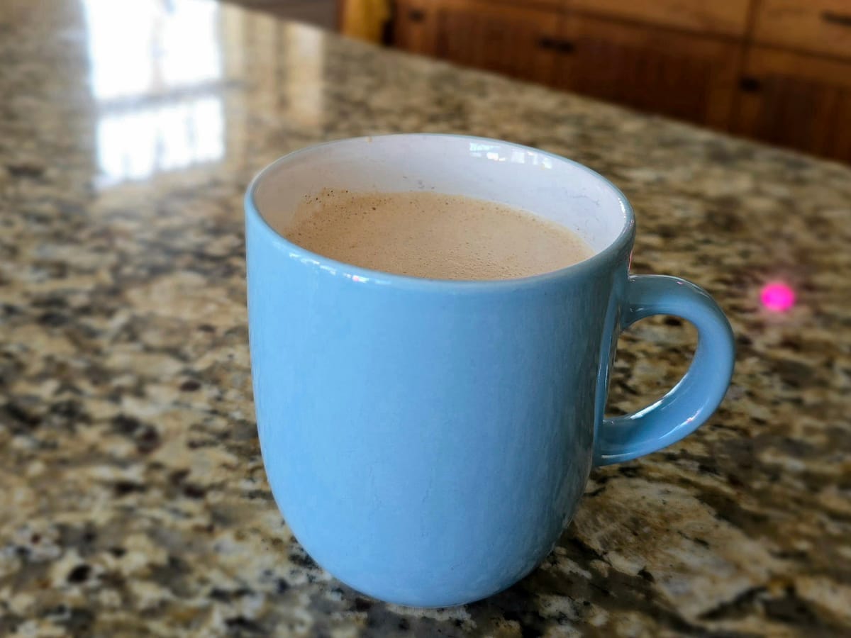 Creamy chai tea latte in a white mug with warm spices, fresh ginger slices, and cinnamon stick garnish