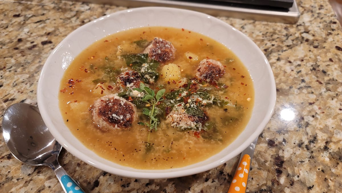 Bowls of Italian wedding soup with tender meatballs, Swiss chard, potatoes, and rich golden broth topped with Parmesan cheese