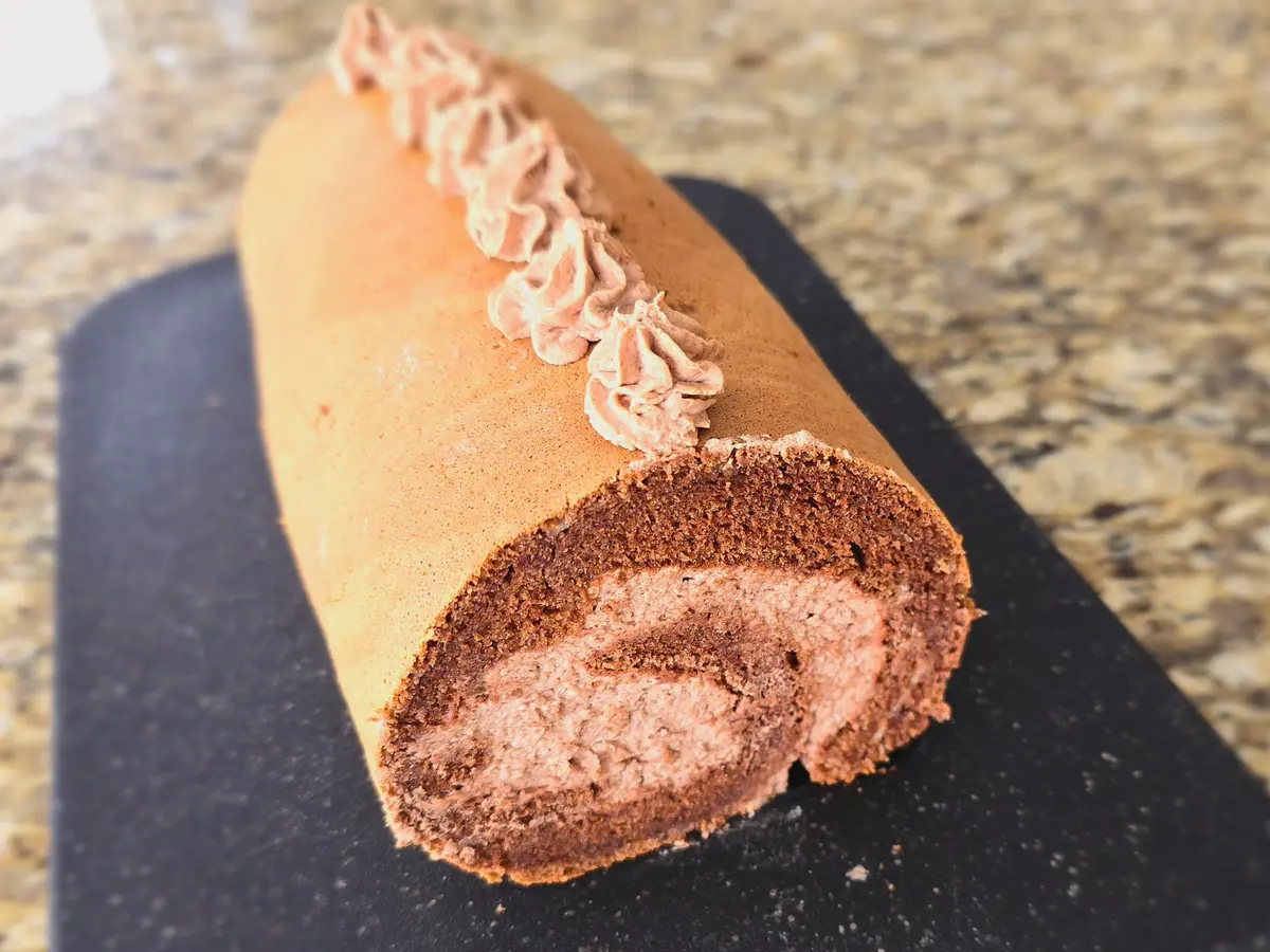 Chocolate Japanese cake roll sliced to show light fluffy sponge interior with rich chocolate flavor on white plate