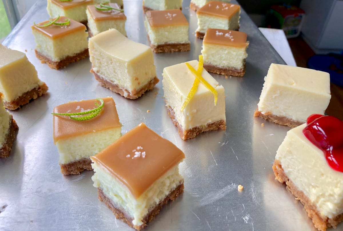 Lime cheesecake bars with salted butterscotch topping and buttery pecan crust, sliced and plated on white surface with sparkly garnish
