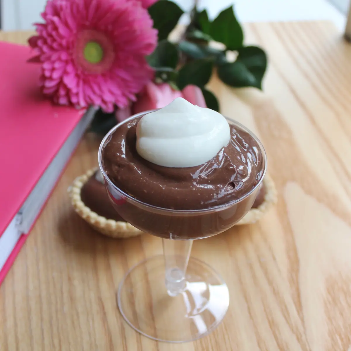 Creamy velvety chocolate pudding in a white bowl with whipped cream and chocolate shavings on top
