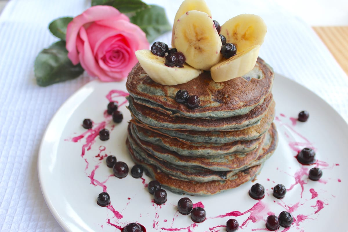 Stack of golden fluffy buttermilk pancakes with melted butter on a white plate