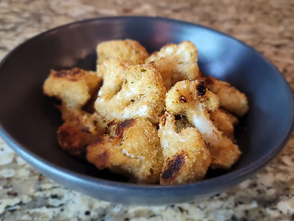 Golden crispy Parmesan cauliflower florets with breadcrumb coating on a white plate