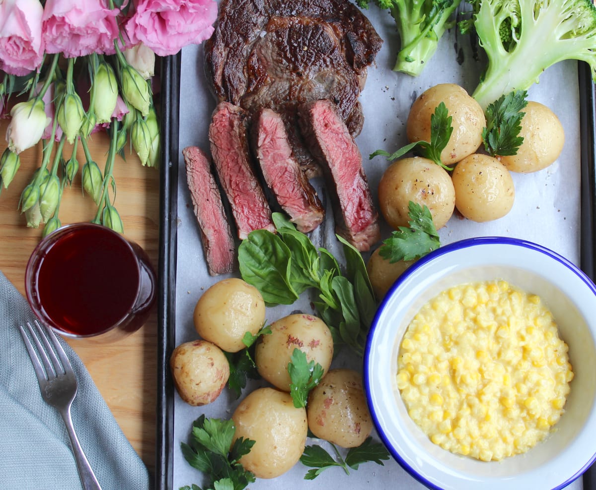 Perfect golden-brown seared ribeye steak on a white plate with herb butter and fresh rosemary garnish