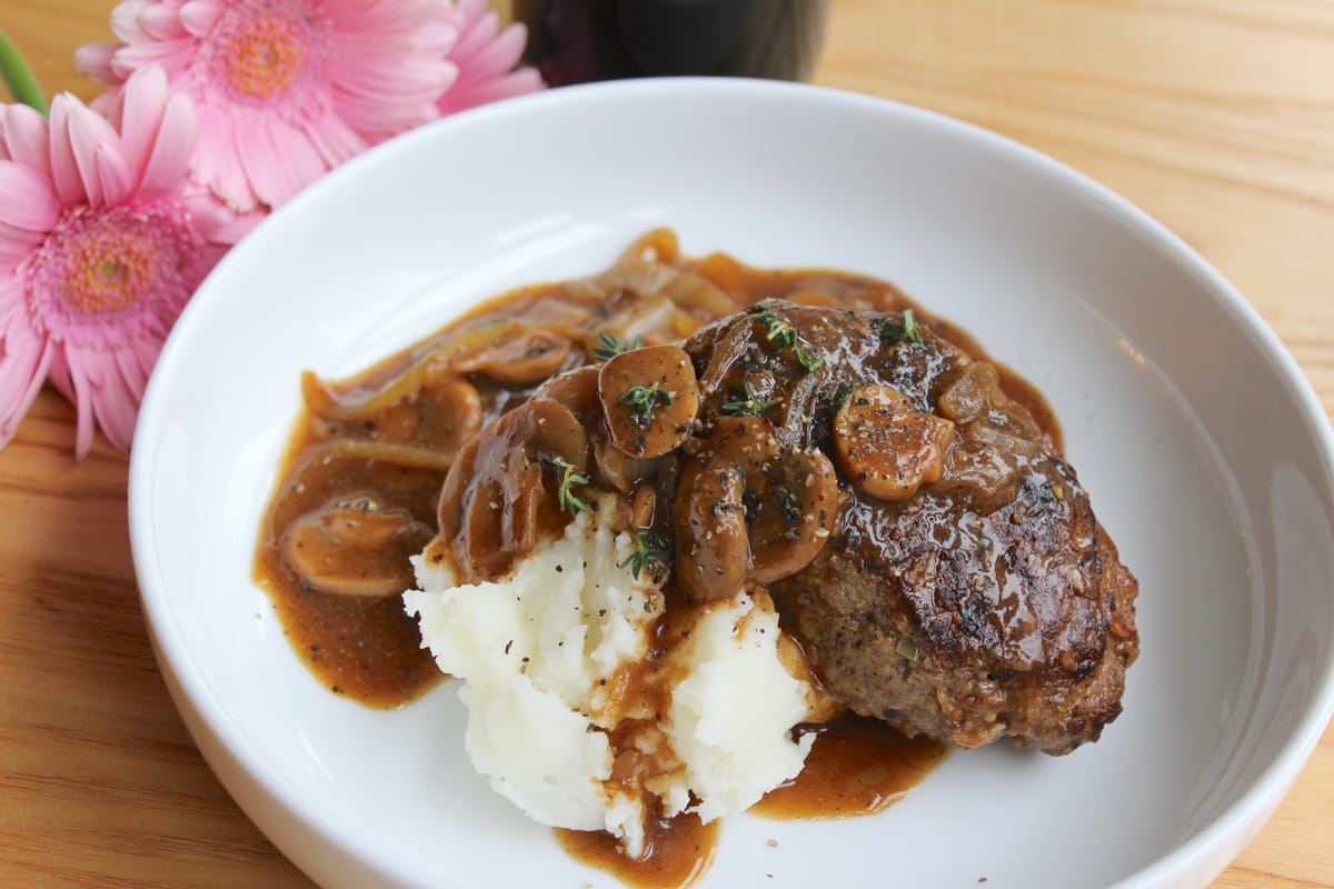Golden-brown oven-baked Salisbury steak patties covered in rich gravy on a white plate