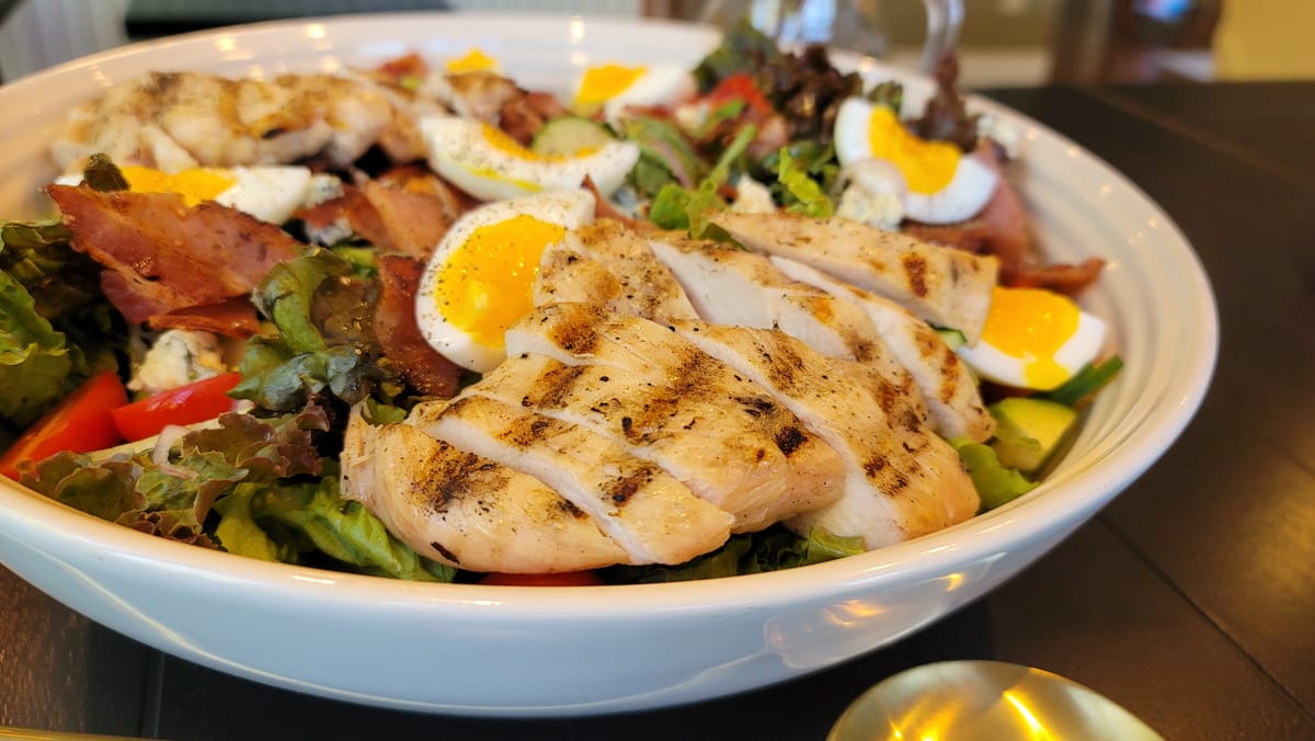 Juicy grilled chicken breasts with golden grill marks on a white plate, garnished with fresh herbs