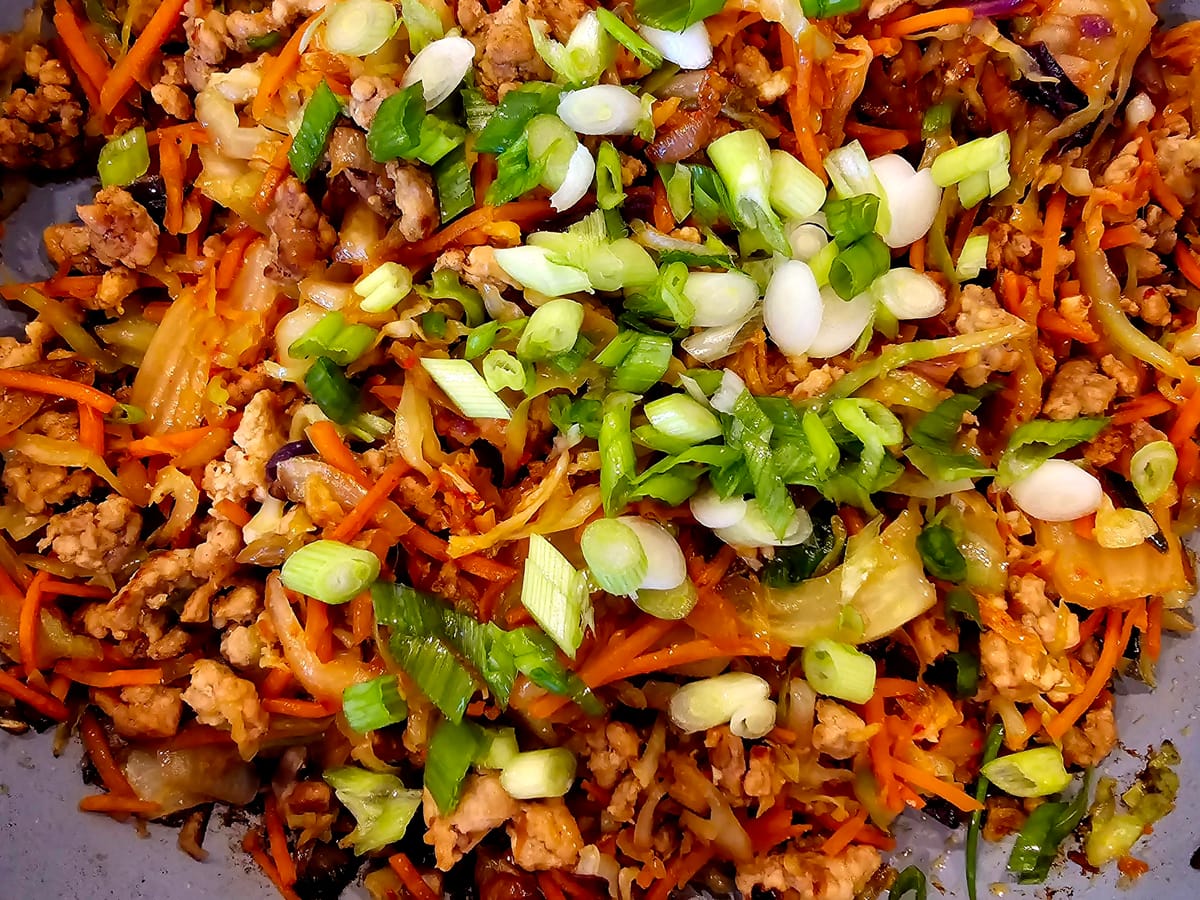 Spring Roll Kimchi Bowl with seasoned ground pork, crispy coleslaw mix, and fresh ginger garnish in a white bowl