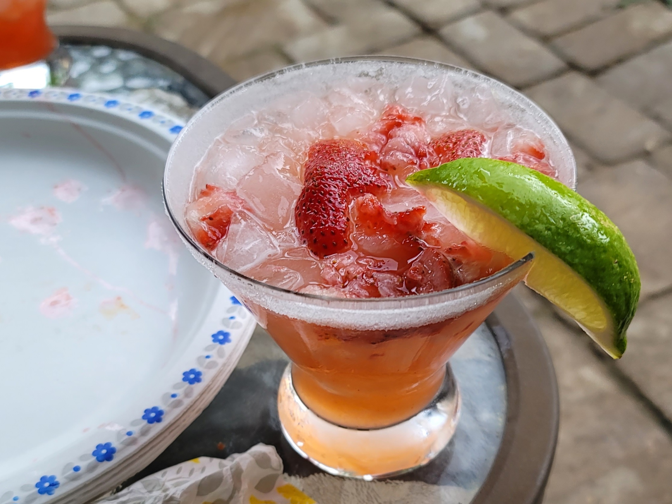 Strawberry margarita in a salt-rimmed glass with fresh strawberries and lime garnish