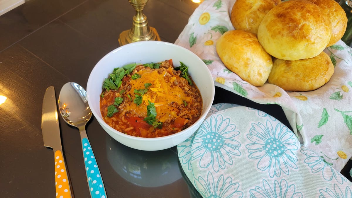 Hearty stuffed pepper soup in a white bowl with colorful bell peppers, ground beef, and tomato broth, garnished with fresh herbs
