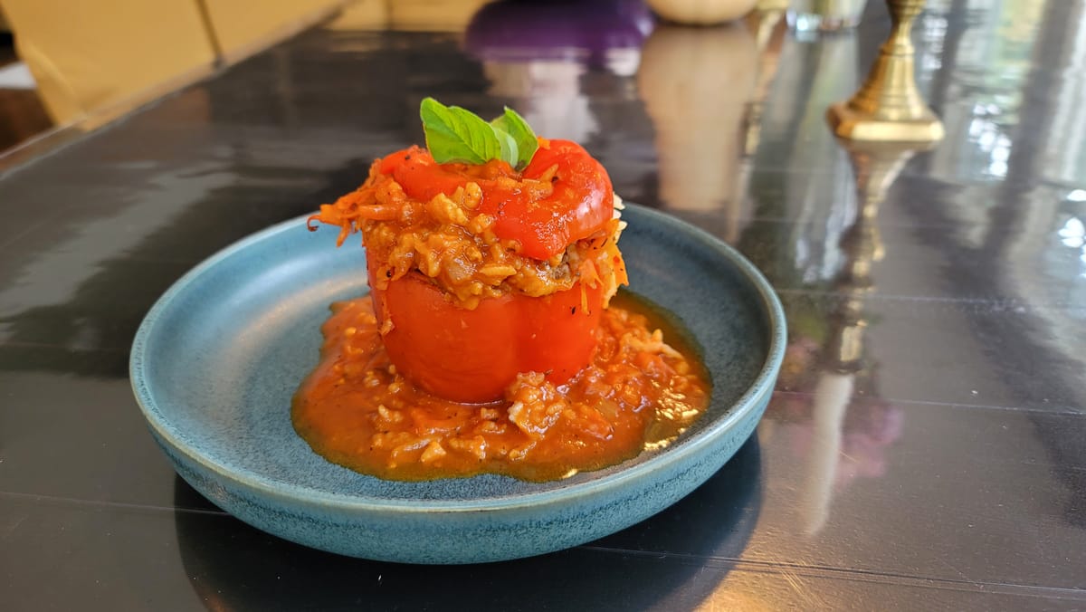 Colorful baked stuffed peppers filled with seasoned ground beef and rice, topped with rich tomato sauce, arranged on a white plate