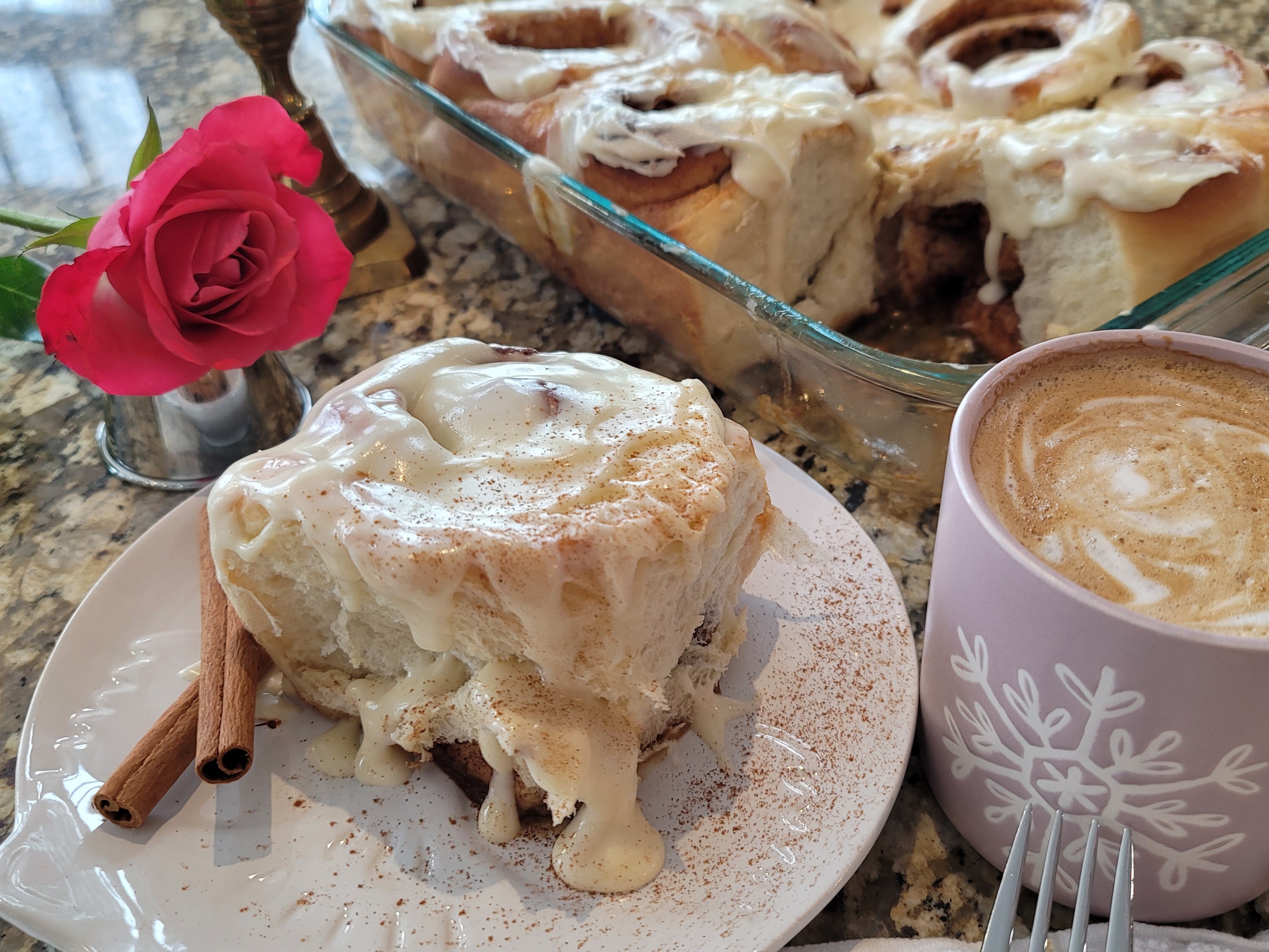 Golden-brown cinnamon buns with cinnamon swirls on a white surface, freshly baked and ready to serve