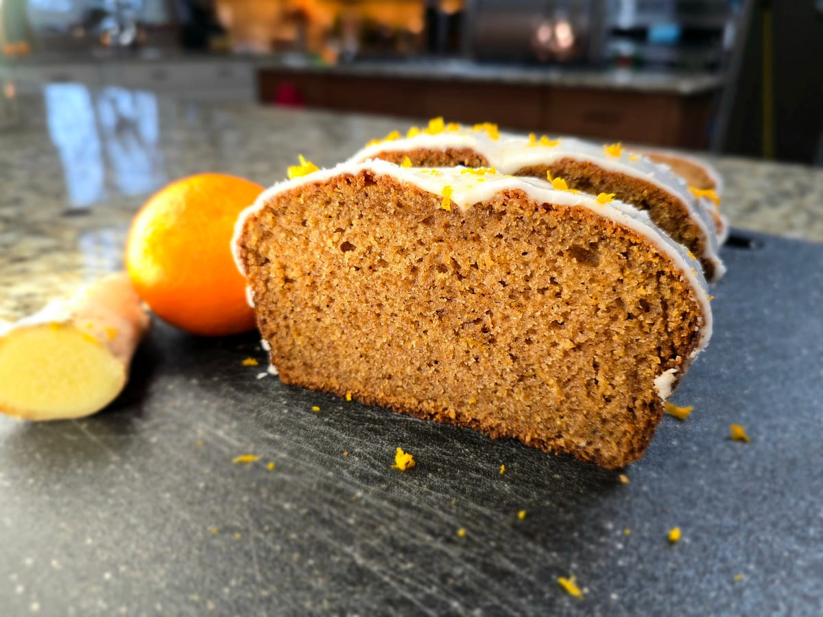 Golden-brown gingerbread loaf with rich spiced crumb, sliced on a white surface showing moist interior