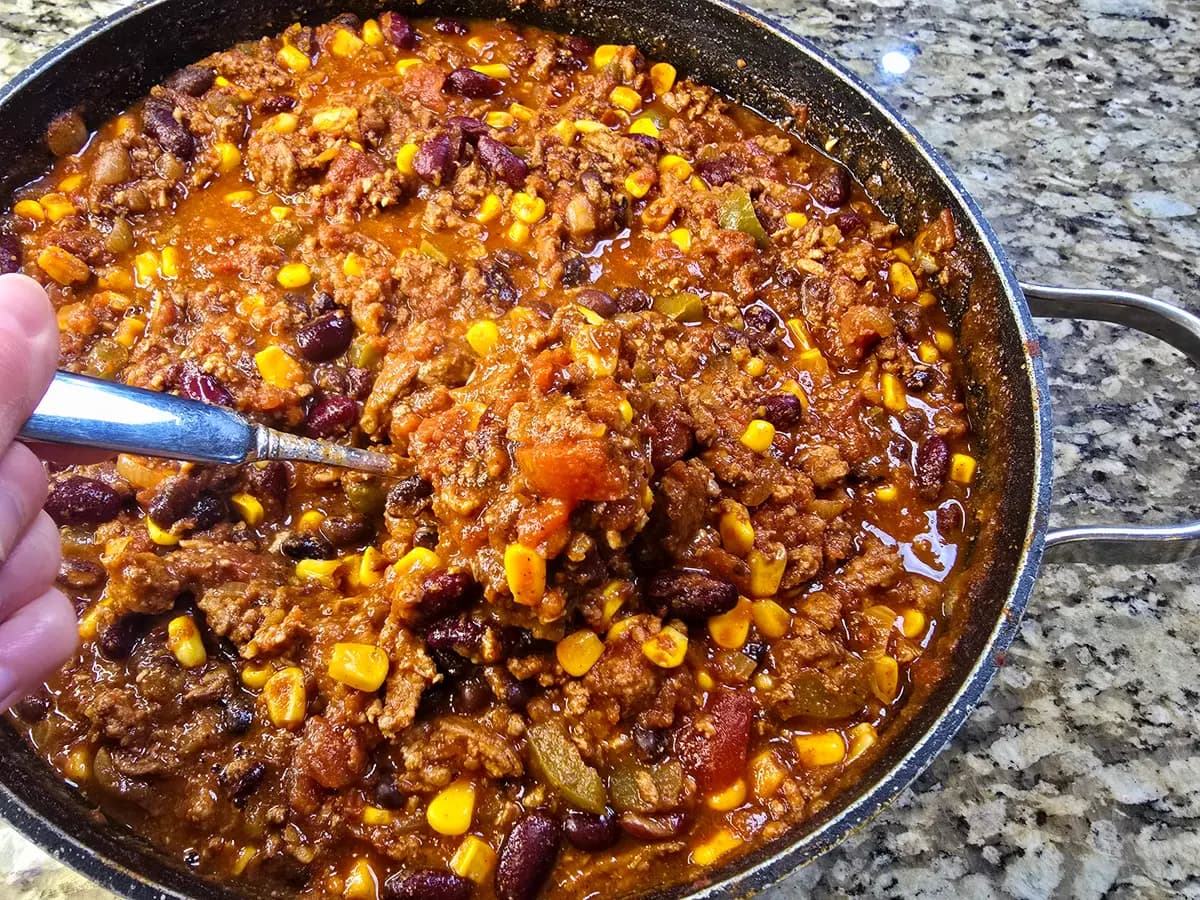 Bowl of best turkey chili with ground turkey, beans, and spices topped with fresh garnish