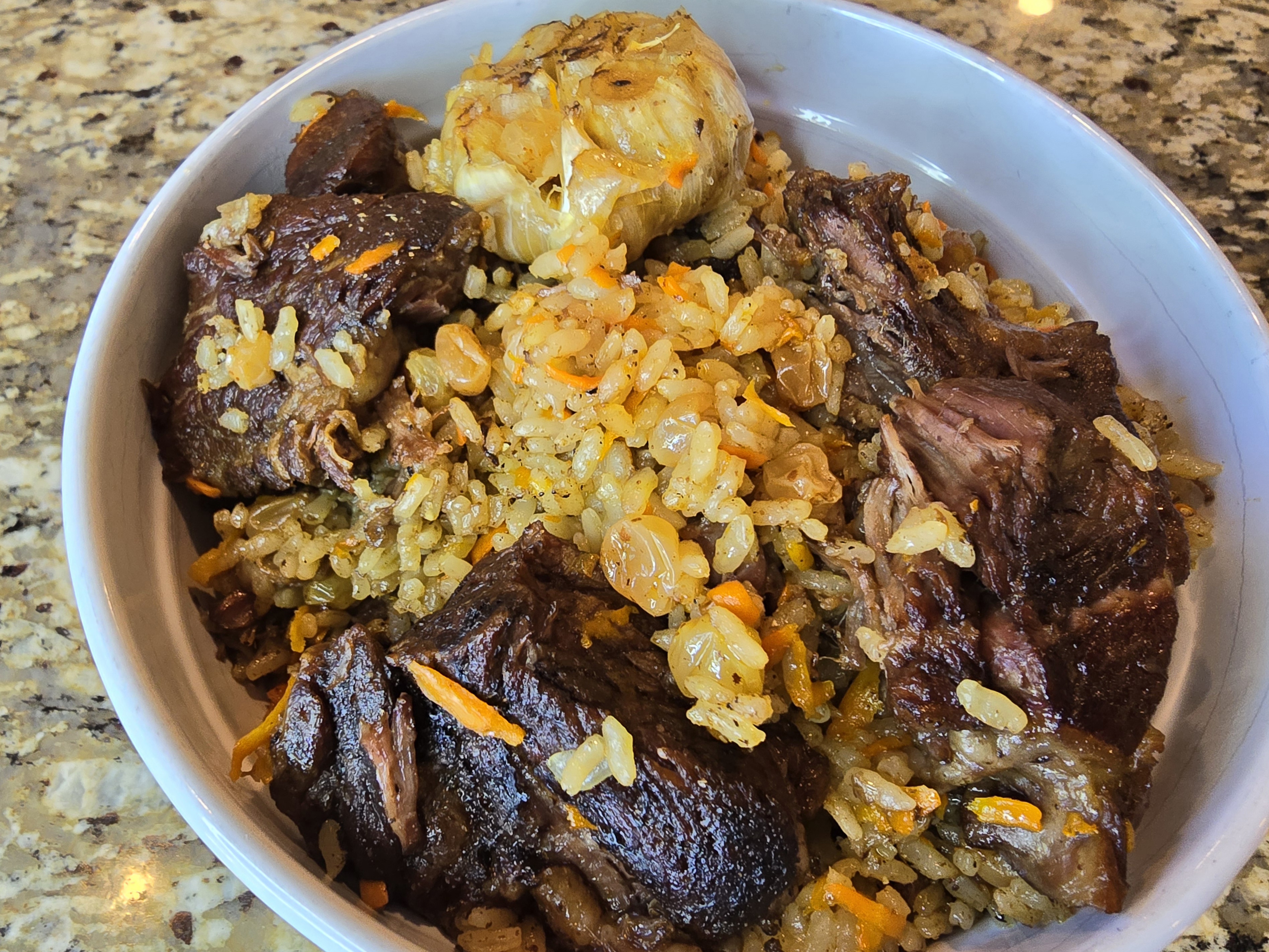 Golden beef plov with tender meat, fluffy rice, and caramelized onions in a serving bowl