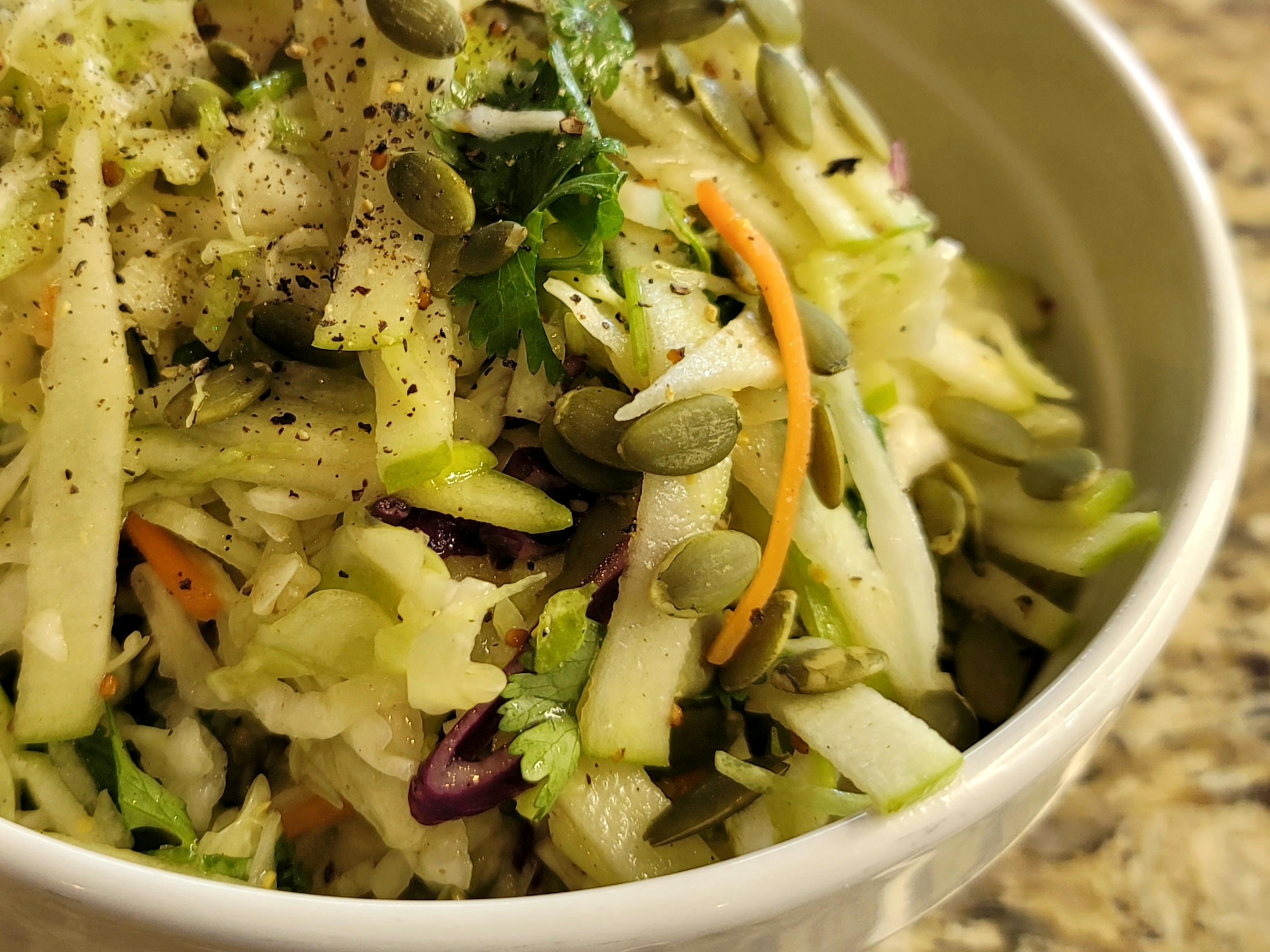 Crisp apple and cabbage salad with fresh cilantro and lime dressing in a white bowl