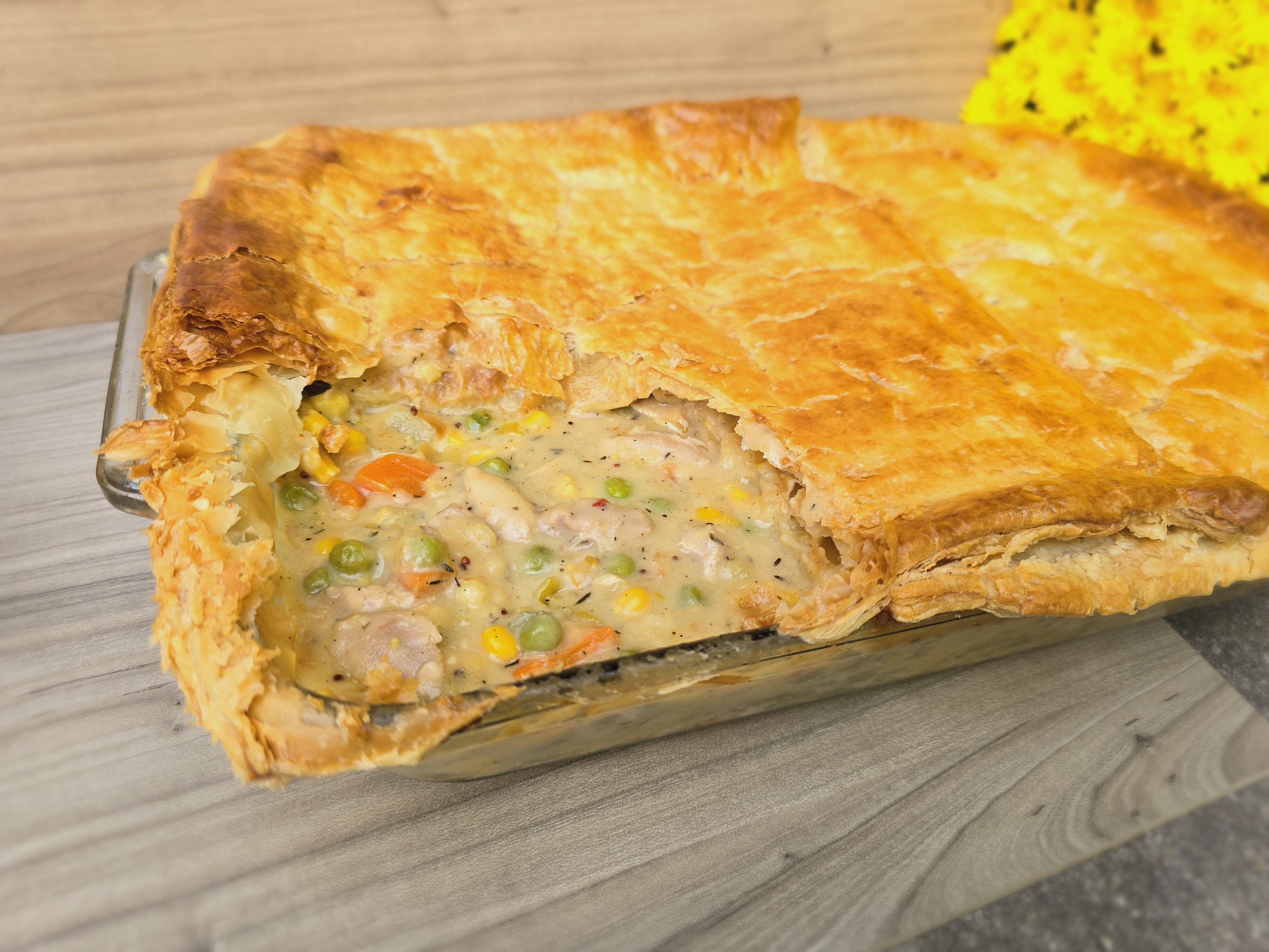 Golden flaky chicken pot pie with creamy chicken and vegetable filling in a ceramic dish