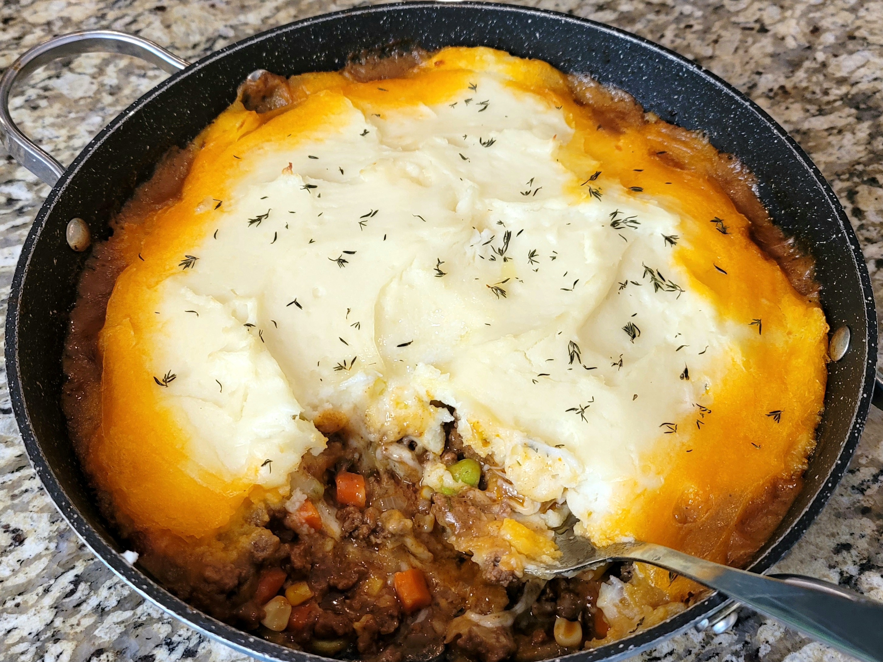 Shepherd's pie with melted cheese curds topping over creamy mashed potatoes and ground beef filling in a baking dish