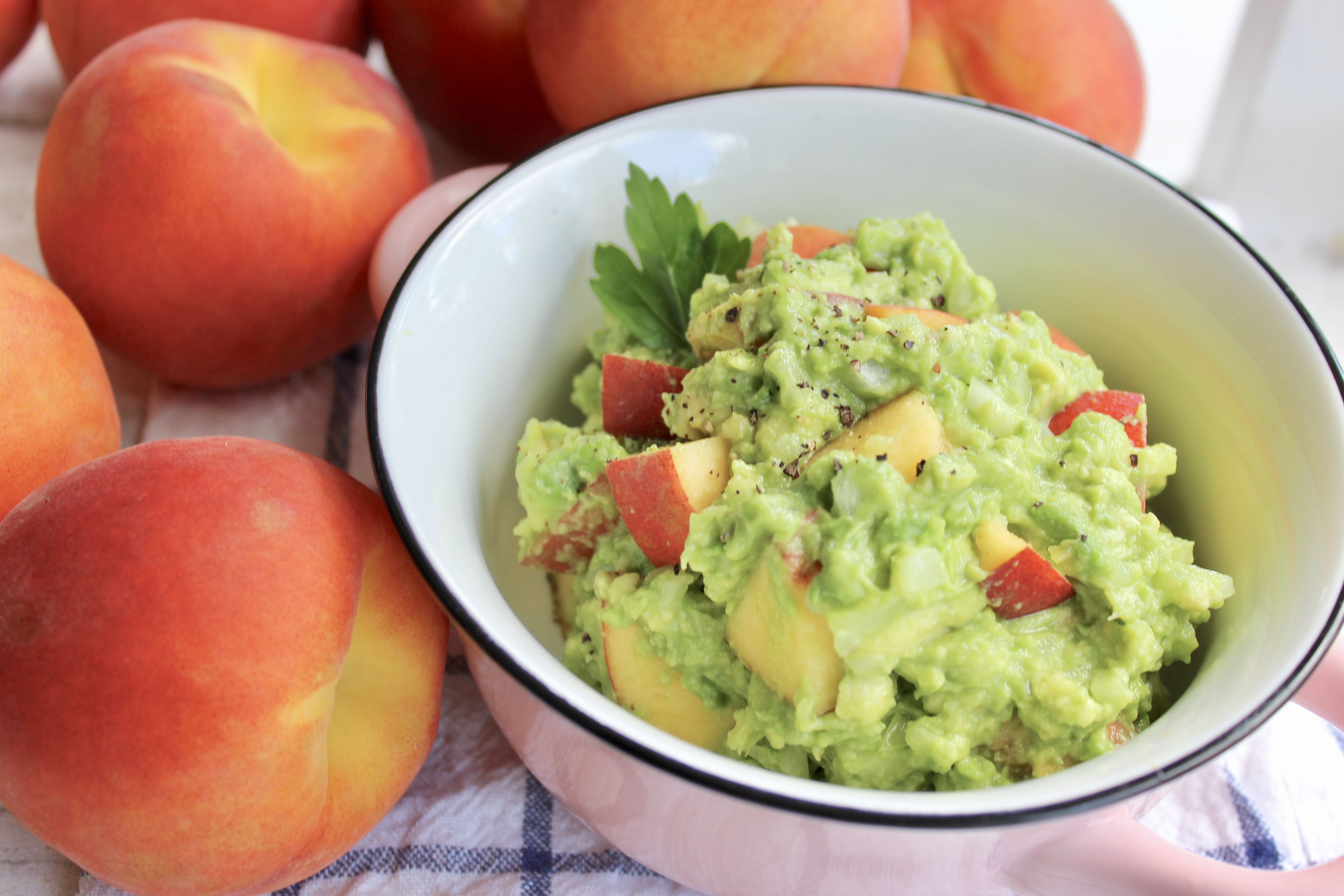 Creamy homemade guacamole in a white bowl with fresh lime, cilantro, and sliced avocado on the side