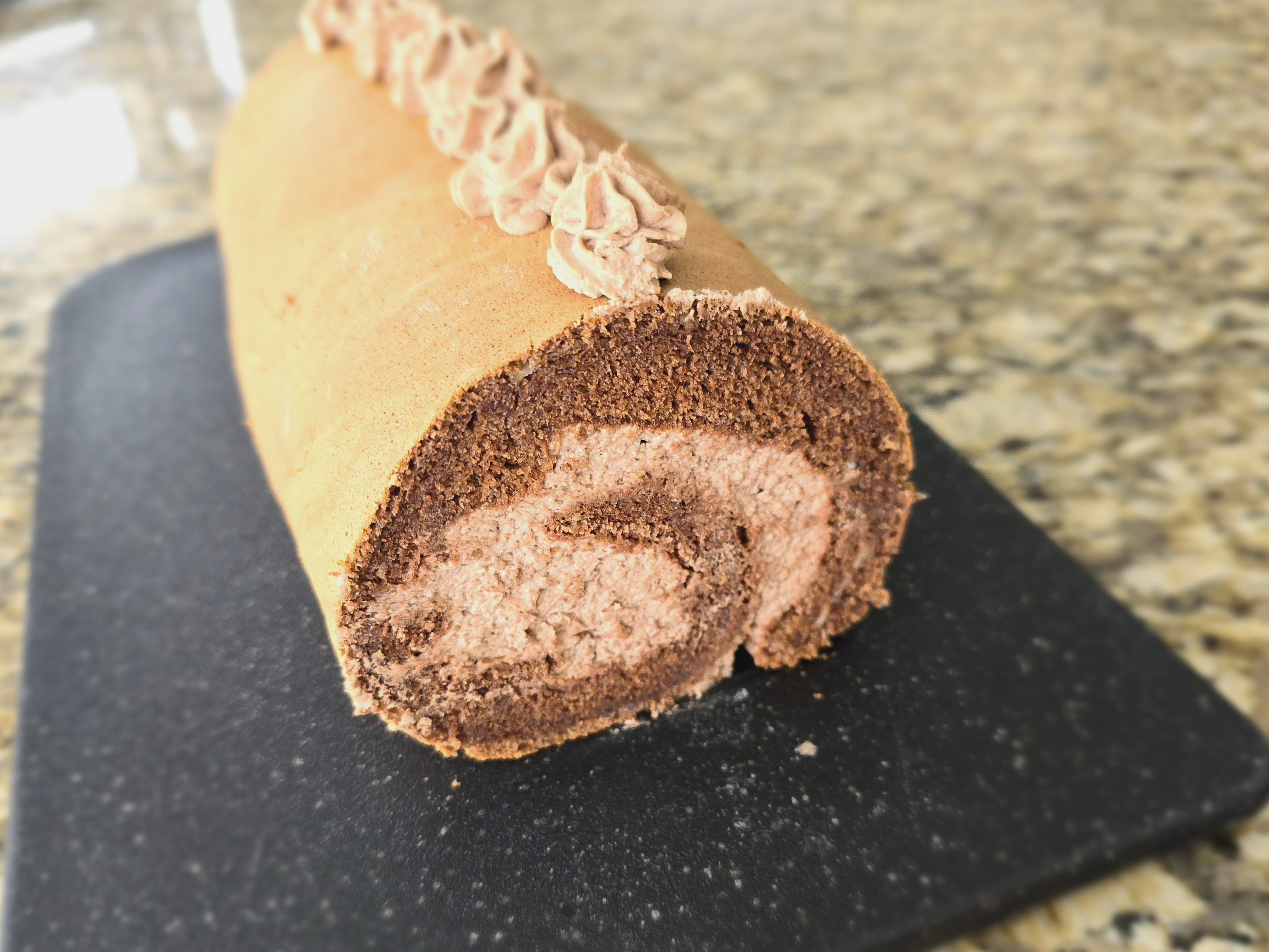 Golden-brown Japanese cake roll sliced to show fluffy sponge layers and creamy filling on a white plate