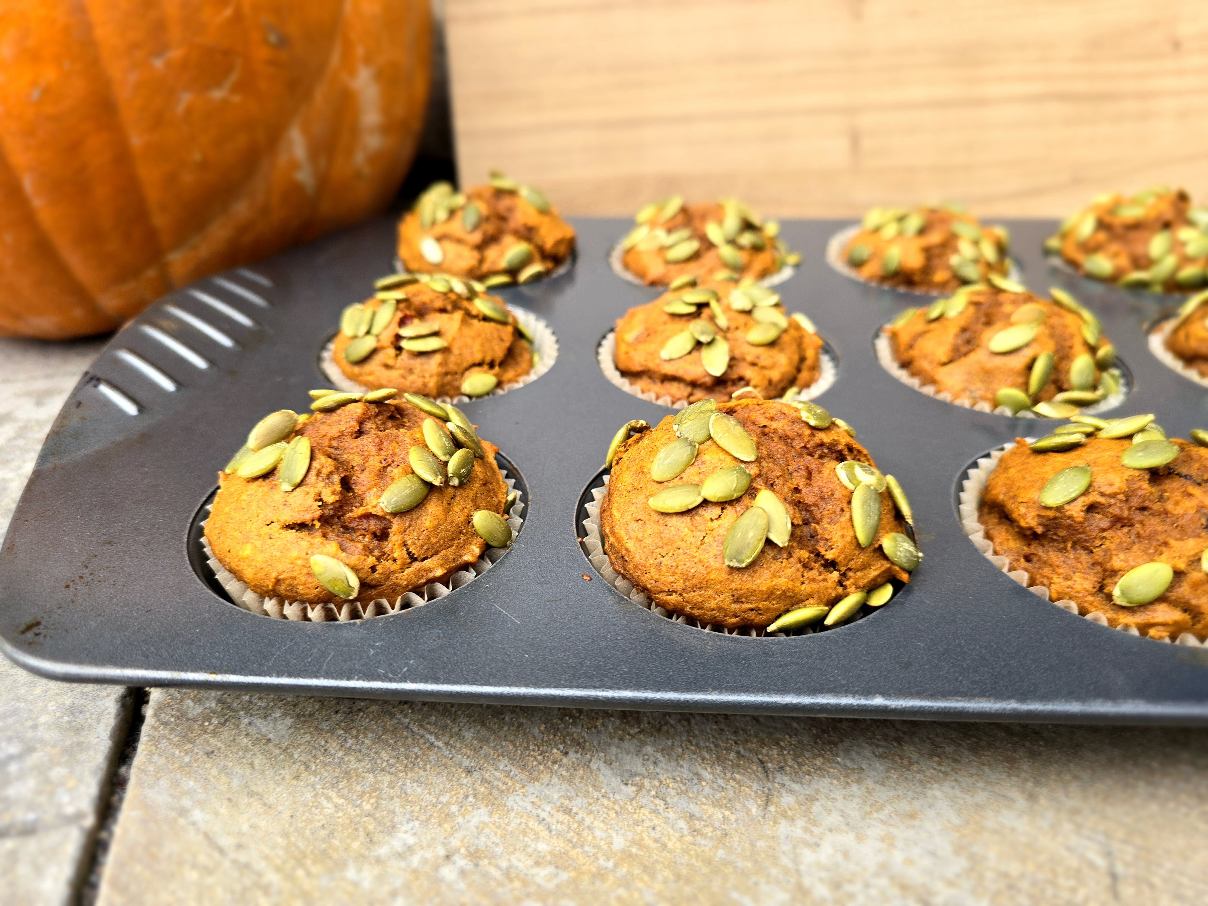 Golden-brown pumpkin muffins stacked on a plate with warm autumn spices and fresh pumpkin puree